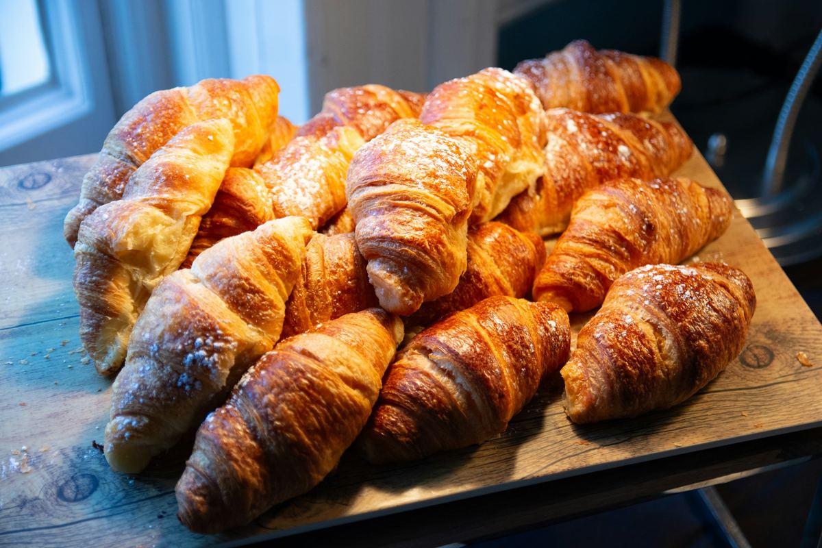 Een plank vol verse croissants met poedersuiker